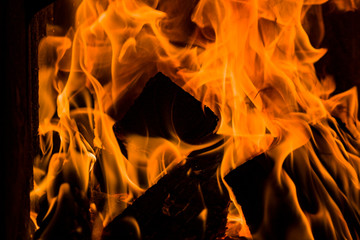 Fire bright burning yellow closeup in the stove on a black background