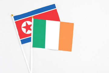 Ireland and North Korea stick flags on white background. High quality fabric, miniature national flag. Peaceful global concept.White floor for copy space.