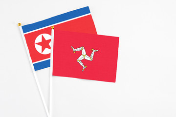 Isle Of Man and North Korea stick flags on white background. High quality fabric, miniature national flag. Peaceful global concept.White floor for copy space.