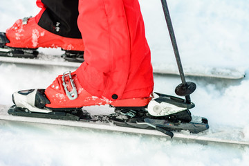 A man is wearing white ski boots in the snow.