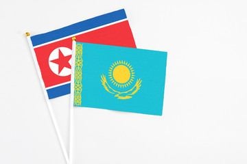 Kazakhstan and North Korea stick flags on white background. High quality fabric, miniature national flag. Peaceful global concept.White floor for copy space.
