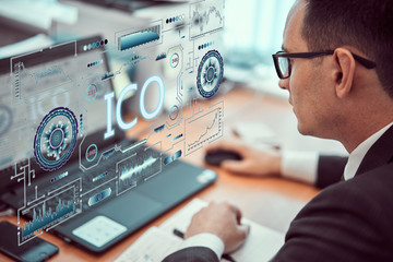 Businessman works behind a laptop with a ICO technology theme hologram. BLOCKCHAIN concept.