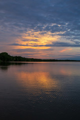 The tranquil waters of Lake Kununurra in the Kimberley region of Western Australia at sunset with tropical thunderstorms in the distance.