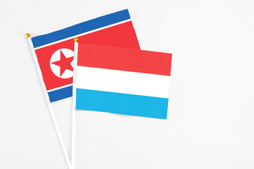 Luxembourg and North Korea stick flags on white background. High quality fabric, miniature national flag. Peaceful global concept.White floor for copy space.