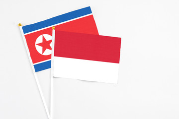 Monaco and North Korea stick flags on white background. High quality fabric, miniature national flag. Peaceful global concept.White floor for copy space.