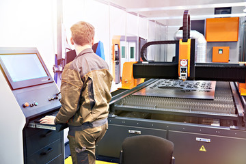Worker on workplace of laser cutting complex for metal