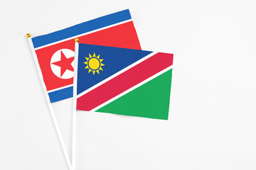 Namibia and North Korea stick flags on white background. High quality fabric, miniature national flag. Peaceful global concept.White floor for copy space.