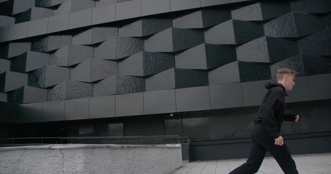 Young man does flips and jumps, parkour on modern city, free running in slow motion.