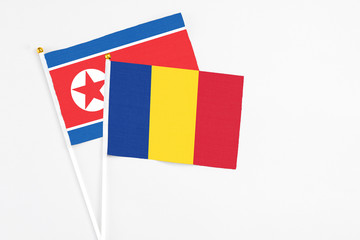 Romania and North Korea stick flags on white background. High quality fabric, miniature national flag. Peaceful global concept.White floor for copy space.