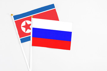 Russia and North Korea stick flags on white background. High quality fabric, miniature national flag. Peaceful global concept.White floor for copy space.