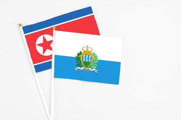 San Marino and North Korea stick flags on white background. High quality fabric, miniature national flag. Peaceful global concept.White floor for copy space.