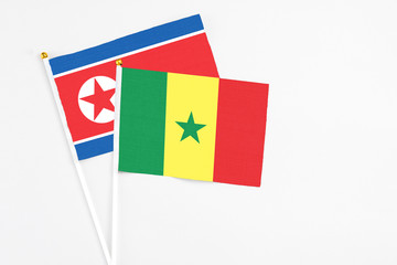 Senegal and North Korea stick flags on white background. High quality fabric, miniature national flag. Peaceful global concept.White floor for copy space.