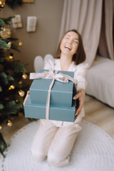 christmas, x-mas, winter, happiness concept - smiling woman with many gift boxes. Girl opens a gift against the background of the Christmas tree. happy young woman celebrating Christmas
