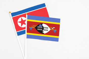 Swaziland and North Korea stick flags on white background. High quality fabric, miniature national flag. Peaceful global concept.White floor for copy space.