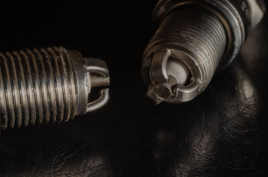 2 car spark plugs on a dark background. View from the side of the electrode. Macro photo. Selective focus. Landscape photo layout