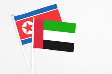 United Arab Emirates and North Korea stick flags on white background. High quality fabric, miniature national flag. Peaceful global concept.White floor for copy space.