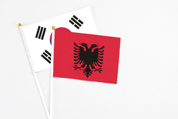 Albania and South Korea stick flags on white background. High quality fabric, miniature national flag. Peaceful global concept.White floor for copy space.