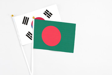 Bangladesh and South Korea stick flags on white background. High quality fabric, miniature national flag. Peaceful global concept.White floor for copy space.