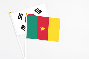 Cameroon and South Korea stick flags on white background. High quality fabric, miniature national flag. Peaceful global concept.White floor for copy space.