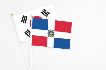 Dominican Republic and South Korea stick flags on white background. High quality fabric, miniature national flag. Peaceful global concept.White floor for copy space.