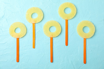 Pineapple rings on blue background, top view. Lollipops