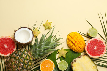 Exotic fruits and palm leaves on beige background, space for text