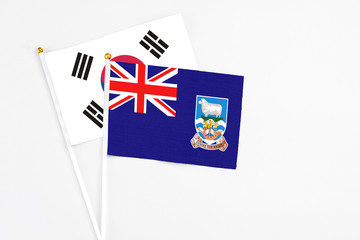 Fototapeta premium Falkland Islands and South Korea stick flags on white background. High quality fabric, miniature national flag. Peaceful global concept.White floor for copy space.