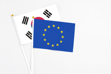European Union and South Korea stick flags on white background. High quality fabric, miniature national flag. Peaceful global concept.White floor for copy space.