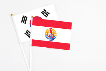 French Polynesia and South Korea stick flags on white background. High quality fabric, miniature national flag. Peaceful global concept.White floor for copy space.