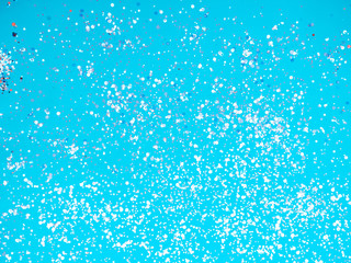 Festive confetti in the blue background, banner. Abstract blue surface with glitter sparkle, party invitation card. Holiday concept