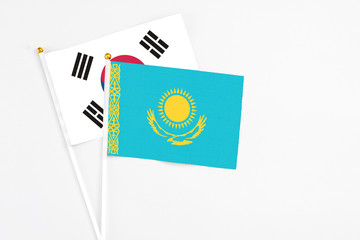 Kazakhstan and South Korea stick flags on white background. High quality fabric, miniature national flag. Peaceful global concept.White floor for copy space.