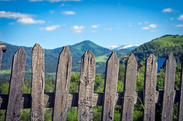 Weathered Timber Picket Fence in the Mountain Village on a Sunny Summer Day. Altai Mountains, Kazakhstan.