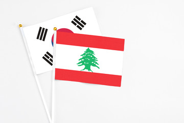 Lebanon and South Korea stick flags on white background. High quality fabric, miniature national flag. Peaceful global concept.White floor for copy space.