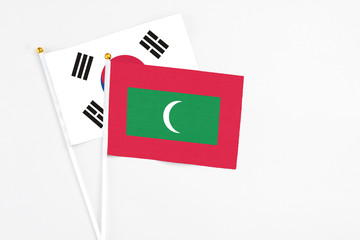 Maldives and South Korea stick flags on white background. High quality fabric, miniature national flag. Peaceful global concept.White floor for copy space.