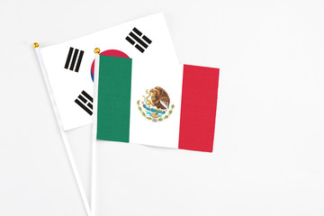 Mexico and South Korea stick flags on white background. High quality fabric, miniature national flag. Peaceful global concept.White floor for copy space.