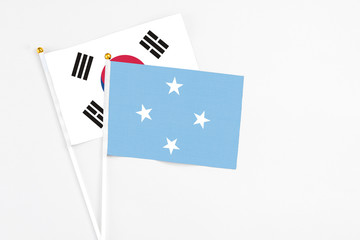 Micronesia and South Korea stick flags on white background. High quality fabric, miniature national flag. Peaceful global concept.White floor for copy space.