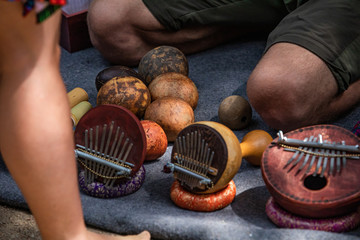 Young man is sitting on a grey blanket demonstrating different world instruments as part of an exhibition in a cultural festival. 