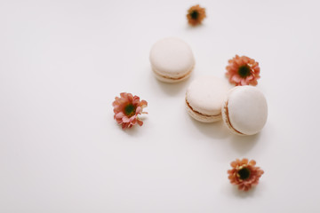 Tasty macarons cookies and flowers on white background. Colorful french desserts. March 8, Spring  background. Valentines, Women, Mothers day concept. Copy space, minimal style, flat lay, top view.