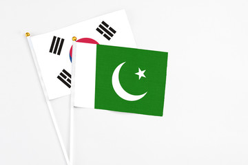 Pakistan and South Korea stick flags on white background. High quality fabric, miniature national flag. Peaceful global concept.White floor for copy space.