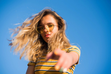 happy teenage attractive girl looks into the camera on the sunny beach over the blue sky wearing...