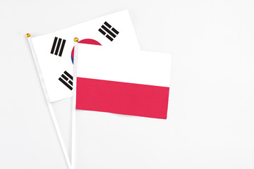 Poland and South Korea stick flags on white background. High quality fabric, miniature national flag. Peaceful global concept.White floor for copy space.
