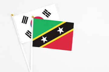 Saint Kitts And Nevis and South Korea stick flags on white background. High quality fabric, miniature national flag. Peaceful global concept.White floor for copy space.