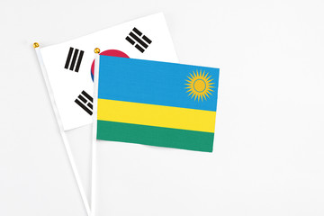 Rwanda and South Korea stick flags on white background. High quality fabric, miniature national flag. Peaceful global concept.White floor for copy space.