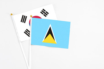 Saint Lucia and South Korea stick flags on white background. High quality fabric, miniature national flag. Peaceful global concept.White floor for copy space.