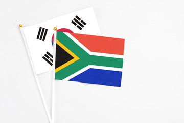 South Africa and South Korea stick flags on white background. High quality fabric, miniature national flag. Peaceful global concept.White floor for copy space.
