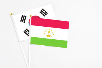 Tajikistan and South Korea stick flags on white background. High quality fabric, miniature national flag. Peaceful global concept.White floor for copy space.