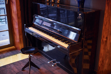 Fototapeta na wymiar Piano and chair indoors in modern restaurant with no people in it