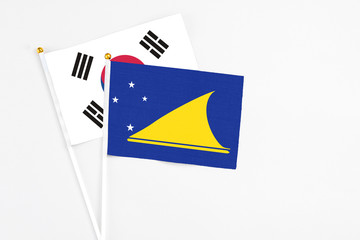 Tokelau and South Korea stick flags on white background. High quality fabric, miniature national flag. Peaceful global concept.White floor for copy space.