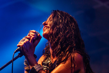 A female musician is viewed from a low angle as she sings and smiling with the audience during a...