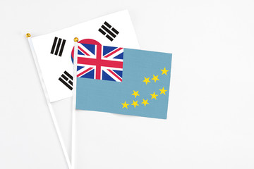 Fototapeta premium Tuvalu and South Korea stick flags on white background. High quality fabric, miniature national flag. Peaceful global concept.White floor for copy space.